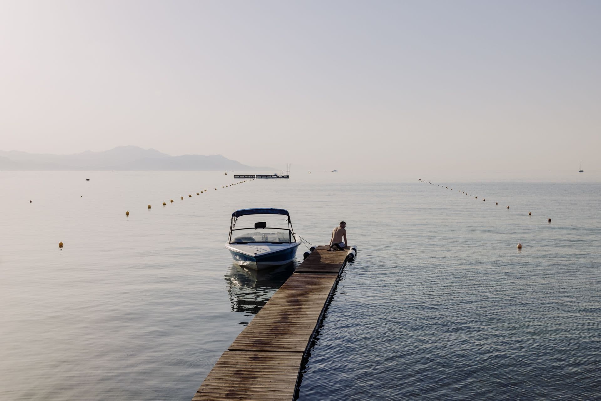 Solo guest sitting on the pier of Cabo by Mayor Hotels, overlooking a calm sea is the perfect way to soak up the charm of Corfu in Autumn.