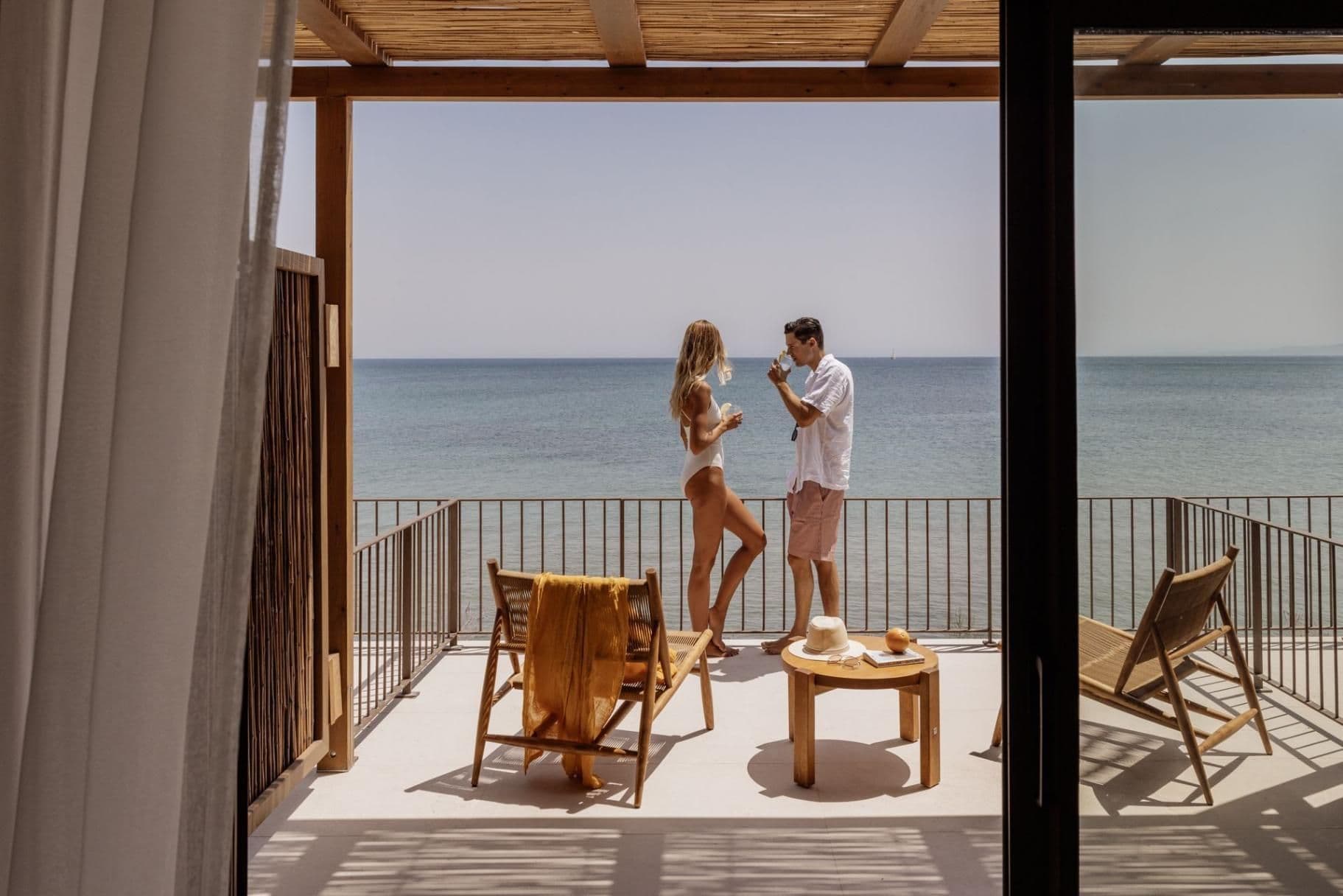 Couple on balcony with the endless blue in front of them, during their holidays at Mayor Cabo, one of the top all-inclusive hotels in Corfu.